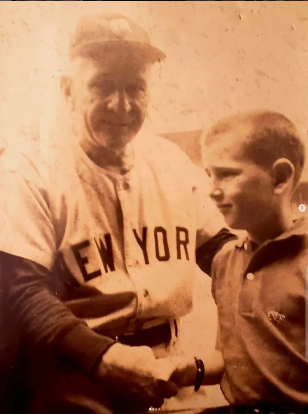 Sepia photograph of Casey Stengel in a New York Yankees uniform shaking hands with a young Robert Rand in the dugout at Tiger Stadium.